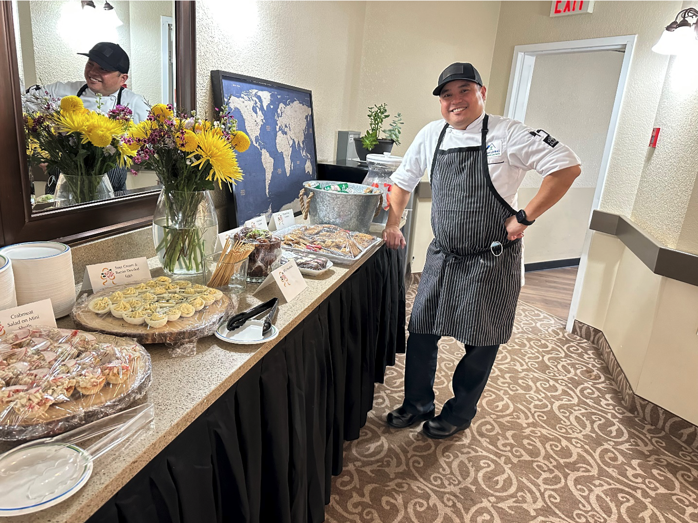 A chef stands next to a table full of finger foods and snacks